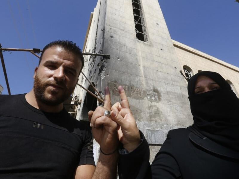 A man and a woman show their ink-stained index fingers after voting for Syria's first local elections since 2011. (LOUAI BESHARA / AFP)