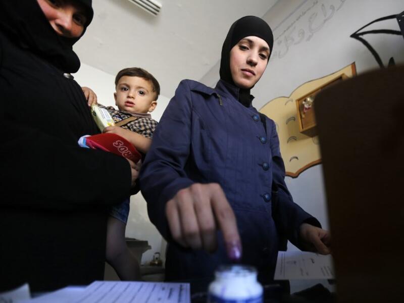 A woman dips her index finger in ink after casting her ballot for Syria's first local elections since 2011, on September 16, 2018. (LOUAI BESHARA / AFP)