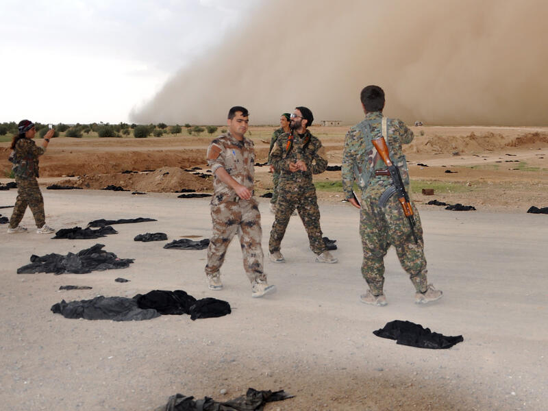 Fighters from the Syrian Democratic Forces stand amongst black abyays discarded by women escaping Daesh territory. (AFP/Ayham al-Mohammad)