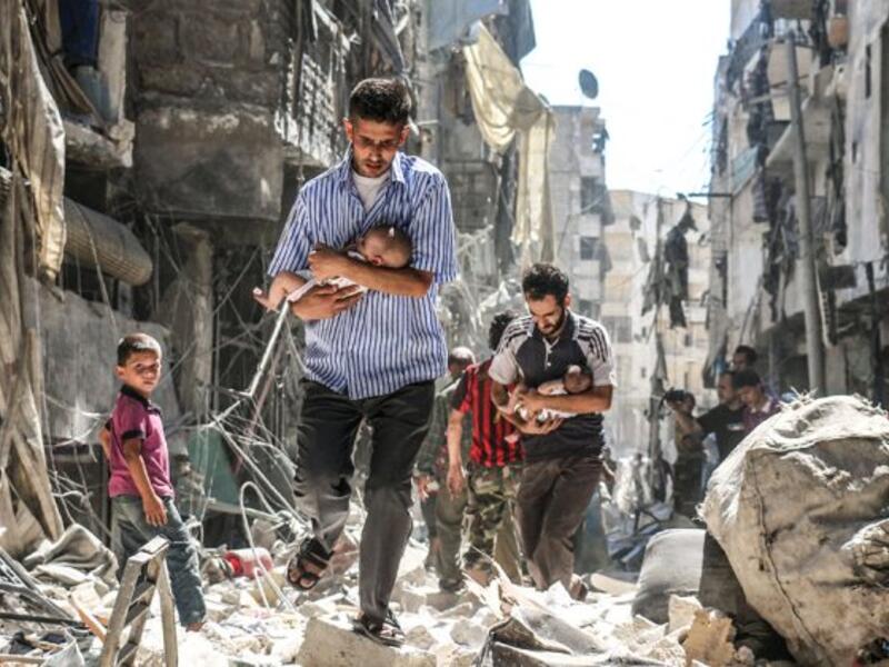 June 9, 2016 – Syrian rescue workers and citizens in Aleppo evacuate people from a building following a barrel bomb attack by Syrian government forces on the rebel held Al-Fardous neighborhood of the northern city of Aleppo. (AFP / AMEER ALHALBI)