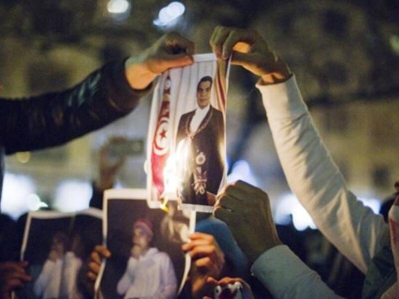 رجال يقومون بحرق صورة للرئيس التونسي بن علي خلال تظاهرة ضده في باريس.