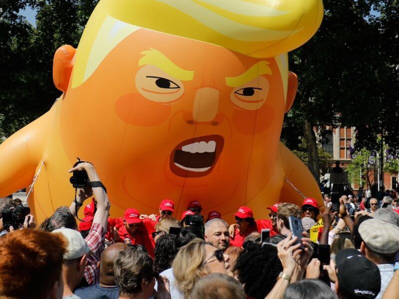 Activists inflate a giant balloon depicting US President Donald Trump as an orange baby during a demonstration against Trump's visit to the UK in Parliament Square in London on July 13, 2018.  (Tolga AKMEN / AFP)