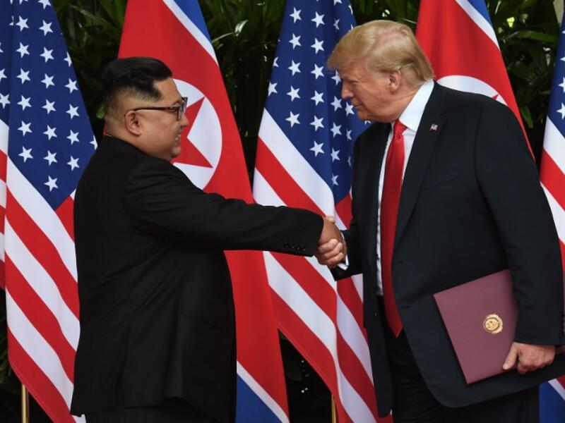 North Korea's leader Kim Jong Un (L) shakes hands with US President Donald Trump (R) after taking part in a signing ceremony at the end of their historic US-North Korea summit, at the Capella Hotel on Sentosa island in Singapore on June 12, 2018. (Anthony WALLACE / POOL / AFP)