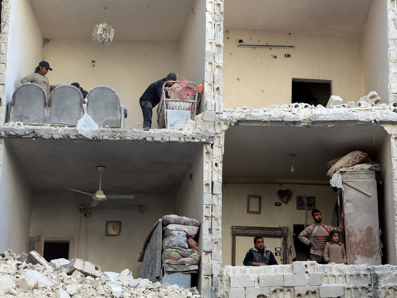 Civilians examine the bombed-out remains of a house in Aleppo, Syria following airstrikes in December 2015.  (AFP/Karam al-Masri)