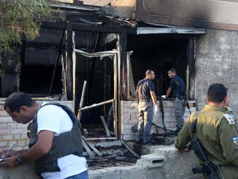 Security forces inspect the West Bank house destroyed in an arson attack on July 31, 2015. (AFP/Jaafar Ashtiyeh)