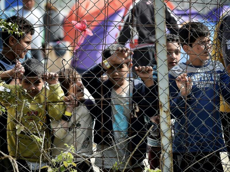 Children stand behind a fence inside the Moria migrant camp transformed in police-run detention facility in Mytilene, on Lesbos island, as they wait to be processed. (AFP/Aris Messinis)