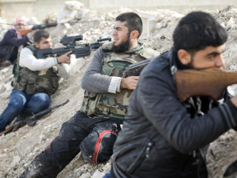 Rebels line a dirt escarpment as they look towards Syrian army positions south of the highway town of Maraat al-Numan on November 17, 2012. [Getty Images]