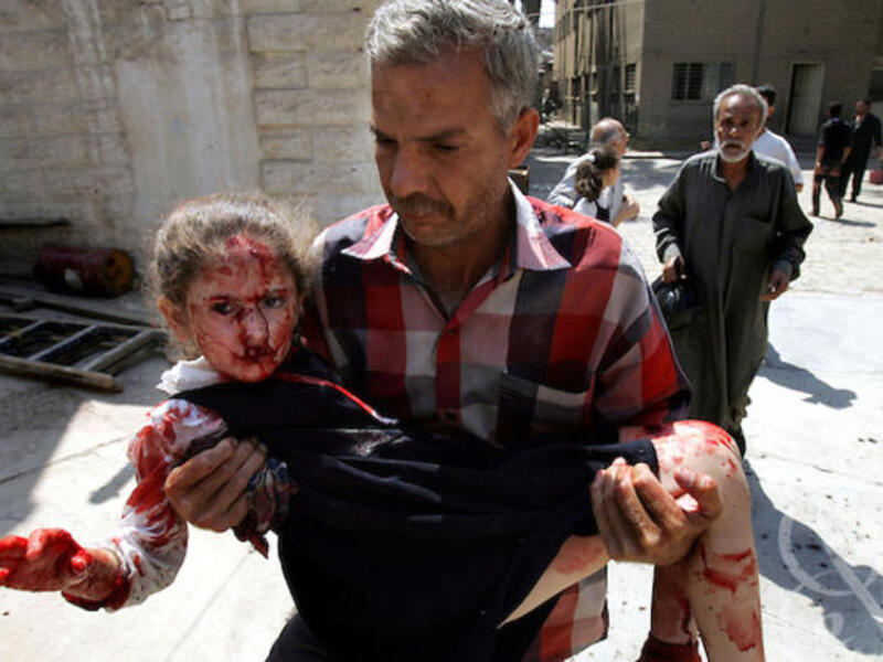 Man carries child from school bombing rubble. [photoshelter]