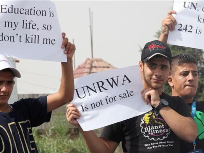 Palestinian refugees living in Jordan hold placards during a demonstration against the planned cuts in services related to the United Nations Relief and Works Agency (UNRWA)’s education program, August 5, 2015. [AFP]