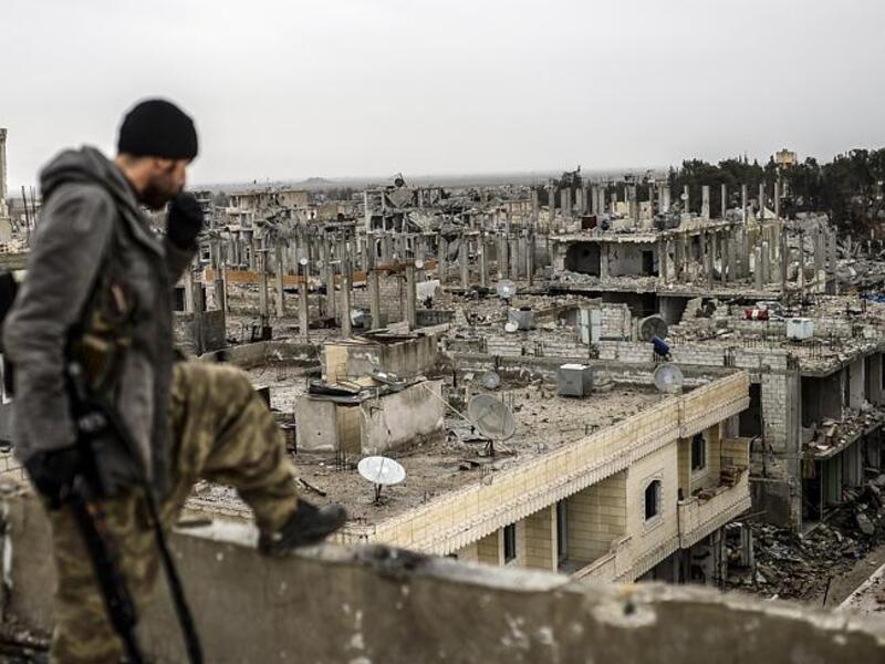 A Kurdish YPG fighter overlooks the destroyed city of Kobani. (AFP/File)