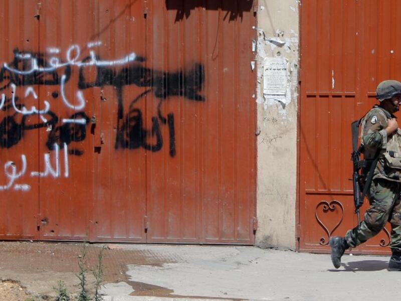 A Lebanese soldier walks past anti-Assad graffiti in the northern city of Tripoli (AFP)