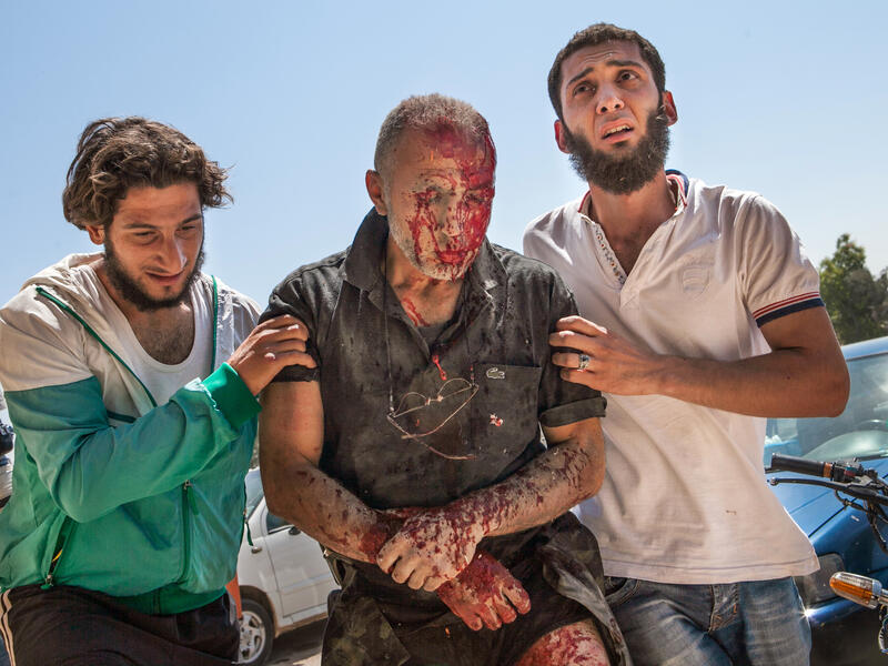 Syrian men rush a heavily wounded man to hospital in Saraqeb in northwestern Syria after a barrel bomb dropped by an air force helicopter exploded less than 10 meters away from his car (AFP/DANIEL LEAL-OLIVAS)