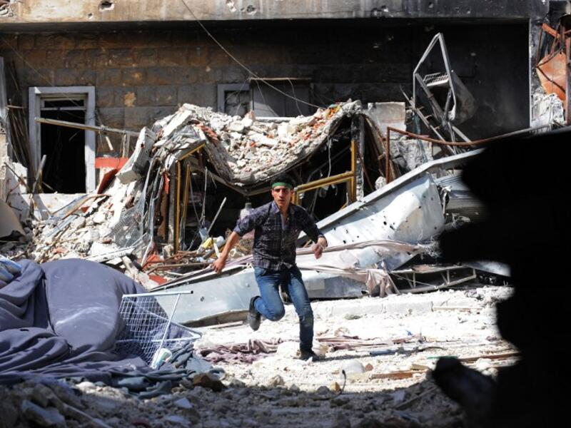 A Syrian opposition fighter runs for cover from Syrian army snipers during clashes in the northern city of Aleppo on March 27, 2013. Syria's President Bashar al-Assad met with a committee tasked with forging a political solution to the country's spiralling conflict, state media said. (AFP PHOTO/BULENT KILIC)
