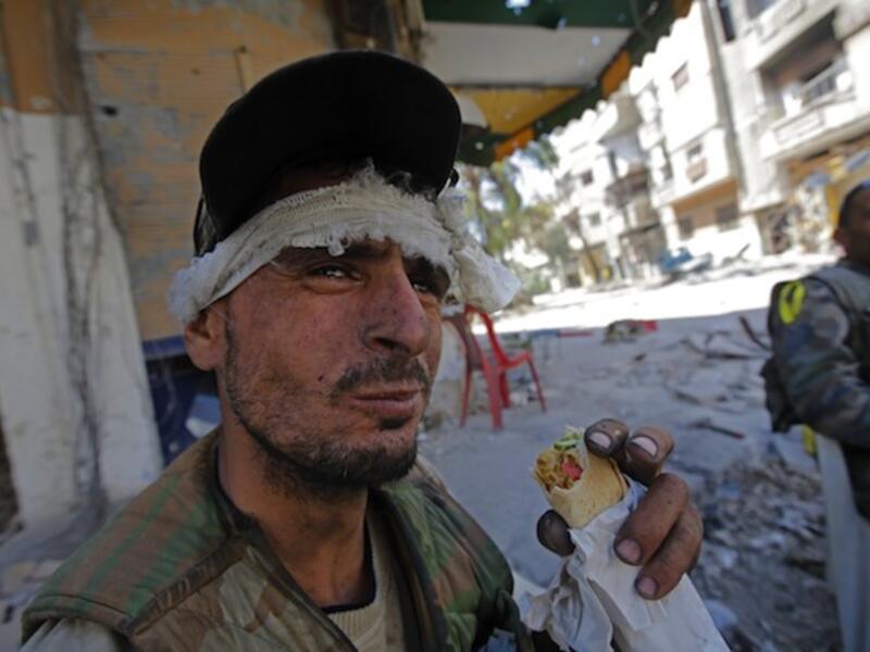 A Syrian government forces soldier eats a sandwich on July 31, 2013 in the al-Khalidiyah district of Syria's central city of Homs. (AFP)