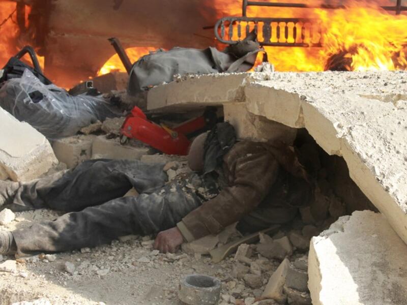 A body seen trapped under rubble after the most recent attack on Aleppo.  More than 130,000 people have been killed in Syria's nearly three-year war. [AFP]