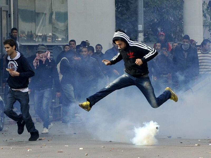 A Tunisian protester jumps amid smoke after police fired tear gas during a rally outside the Interior ministry to protest after Tunisian opposition leader and outspoken government critic Chokri Belaid was shot dead. AFP PHOTO / FETHI BELAID