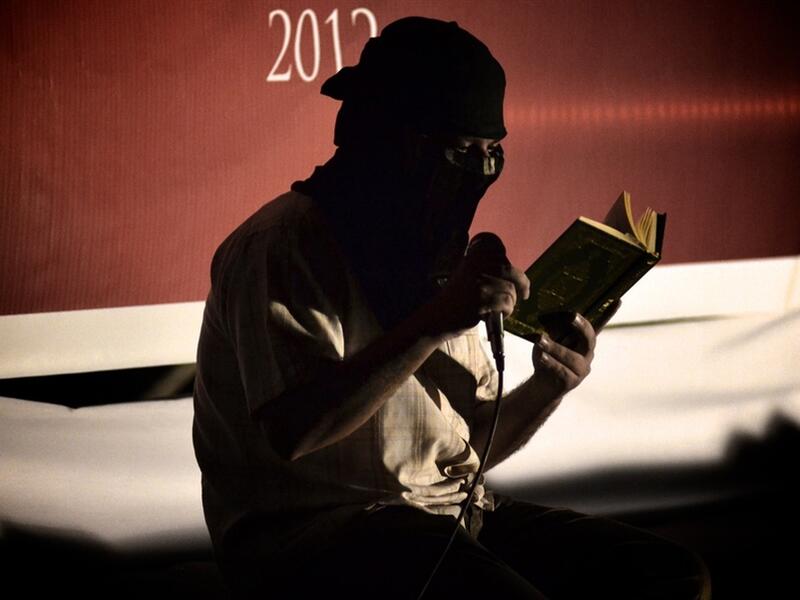 A Shiite Muslim reads the Quran before starting an anti-government rally in 2012. According to recent reports, government forces have damaged a prominent Shiite shrine. (AFP/File)