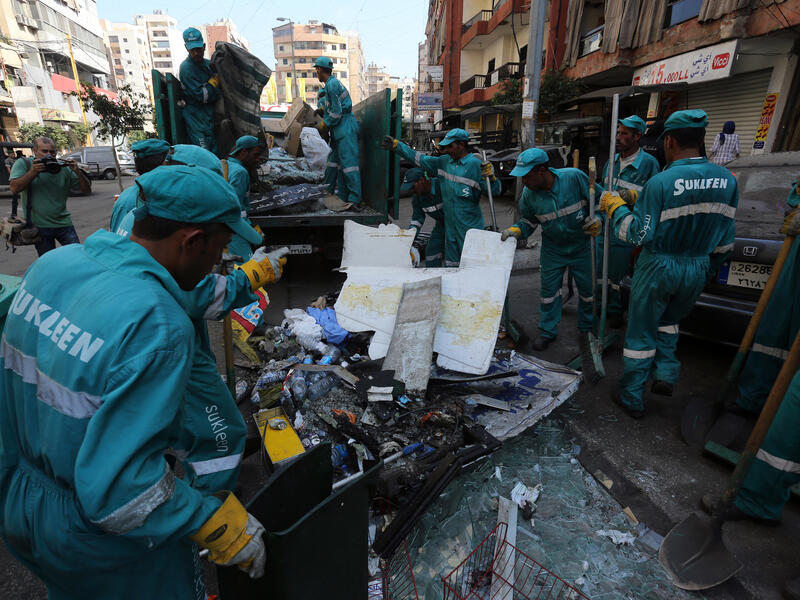 Municipal workers clean up following a car bomb attack the previous day that killed at least 27 people in a Beirut stronghold of Shiite group Hezbollah, which backs Syria's embattled president (AFP/STR)