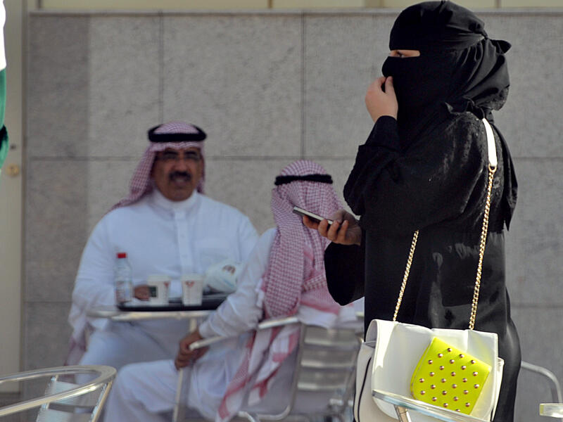 A Saudi woman holds her mobile as she walks through a coffee shop in the capital Riyadh on June 17, 2013. (Source: AFP/ FAYEZ NURELDINE)