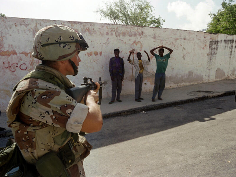 A U.S. Marine points a weapon at gunmen who are surrendering after a Marine patrol confiscated their weapons on December 21, 1992, near the Parliament building along Mogadishu's green line. (AFP)
