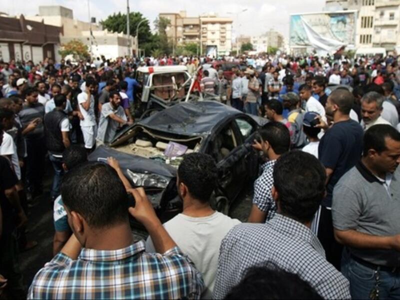 Bystanders and residents gather next to the wreckage of a car at the site of a car bomb that exploded in the parking lot of a Benghazi hospital in Libya on Monday. (AFP Photo)