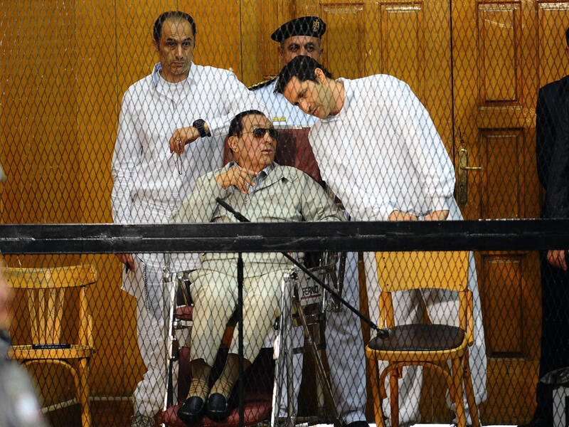 Egyptian toppled president Hosni Mubarak and his two sons Alaa (R) and Gamal stand behind bars during their trial at the Police Academy on September 14, 2013 in Cairo (AFP)