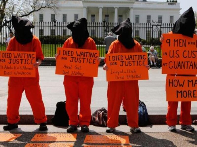 Black hooded human rights activists hold banners demanding the closing of Guantanamo during a protest, part of the Nationwide for Guantanamo Day of Action, outside the White House in Washington DC in April. Photo courtesy of The Week