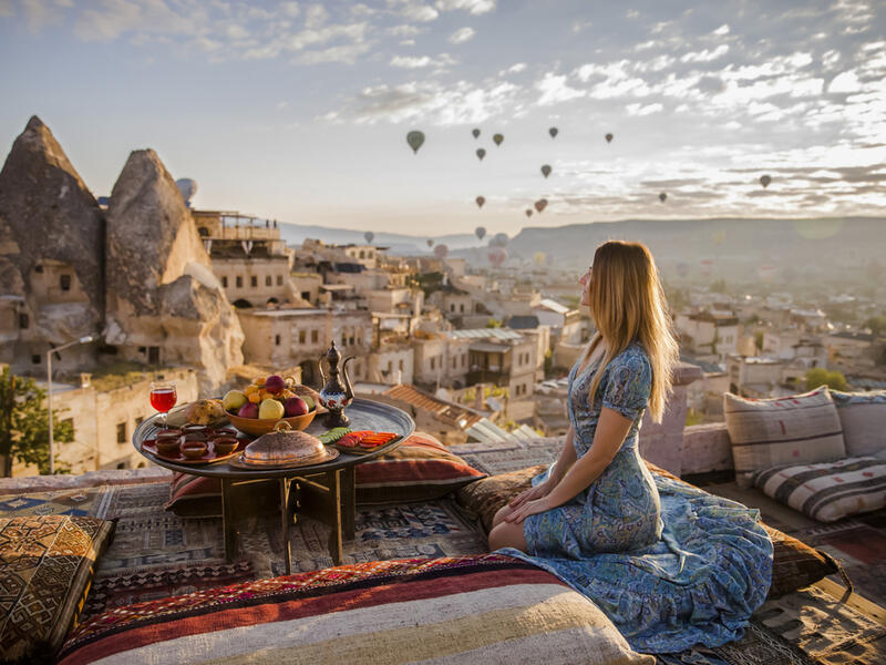 A woman sits on one of the Cappadocia roof in early morning sunrise, when balloons fly (Shutterstock/File Photo)