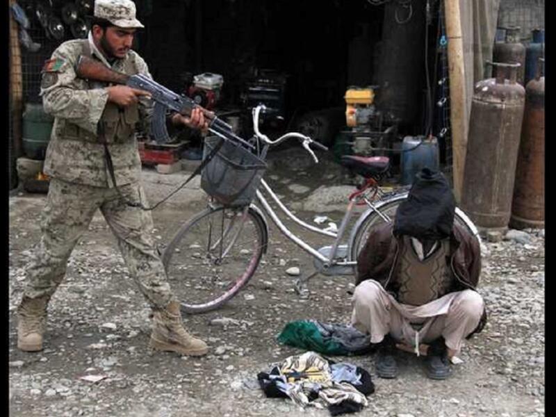 رجل أمن أفغاني يصوب سلاحه تجاه رجل اتهم بتخطيطه لتفجير انتحاري في مدينة جلال أباد بأفغانستان.