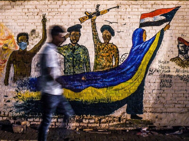A Sudanese protester walks past a recently painted mural during a demonstration near the army headquarters in the capital Khartoum (AFP)