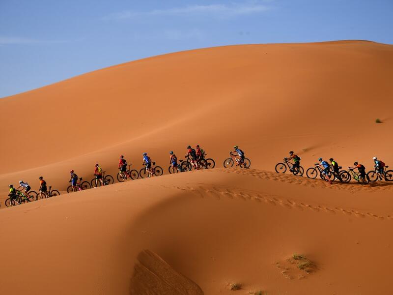 Competitors ride their bikes along sand dunes during the Stage 1 of the 14th edition of Titan Desert 2019 mountain biking race around Merzouga in Morocco on April 28, 2019.  FRANCK FIFE / AFP