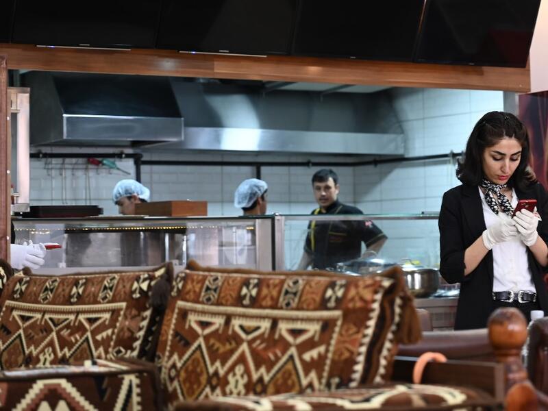 An Afghan waitress checks her smartphone at an Afghan Kebab restaurant at Esenyurt district in Istanbul.  OZAN KOSE / AFP