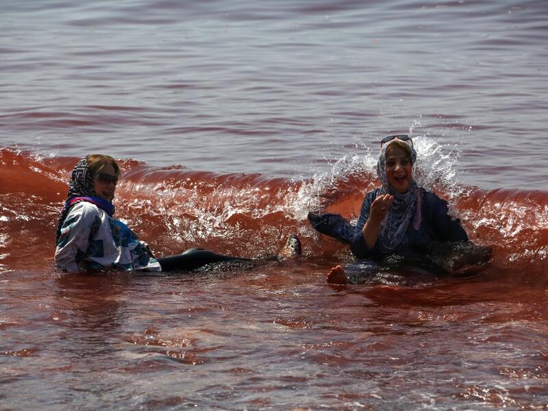 Visitors paddle in the water on the Hormuz Island in the Gulf Strait of Hormuz, off the Iranian port city of Bandar Abbas, on April 29, 2019.  ATTA KENARE / AFP