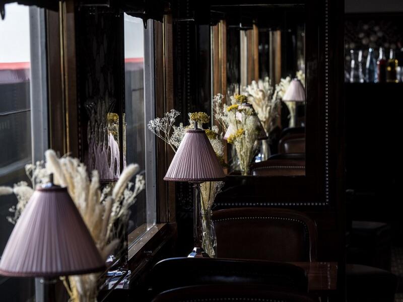 This picture taken on May 13, 2019 shows table lamps and flowers adorning the dining car of a restored carriage of an Orient Express train displayed at the Gare de l'Est train station in Paris.  Christophe ARCHAMBAULT / AFP