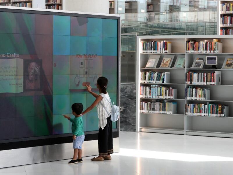 A girl and a boy use a giant interactive display screen at the Qatar National Library in the capital Doha.  KARIM JAAFAR / AFP