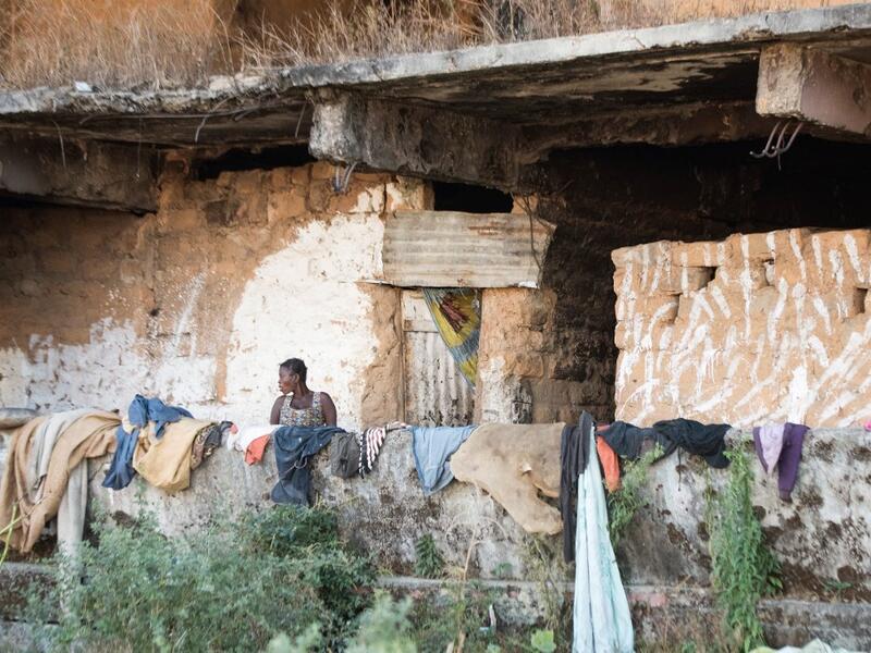 A homeless woman living in a derelict building, damaged during the Angolan civil war, stands by clothes left to dry on its wall RODGER BOSCH / AFP