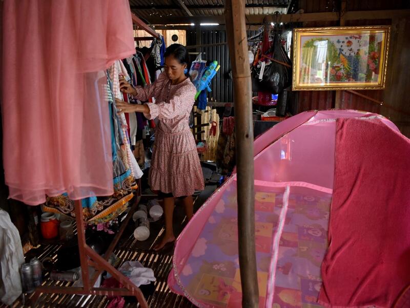 This picture shows a woman arranging clothes inside her home in front of a grave in Phnom Penh.  TANG CHHIN Sothy / AFP