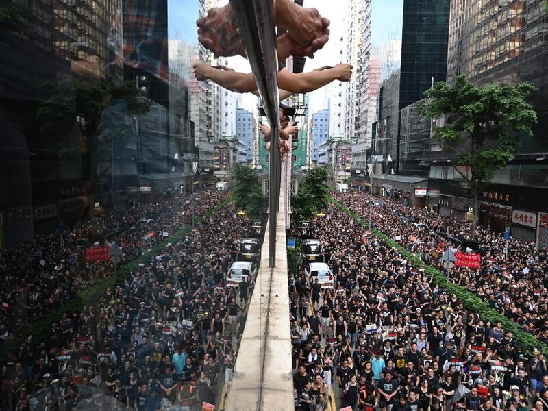  Thousands of protesters (R) dressed in black as reflected on the glass over a balcony (L) as they take part in a new rally against a controversial extradition law proposal in Hong Kong.  HECTOR RETAMAL / AFP
