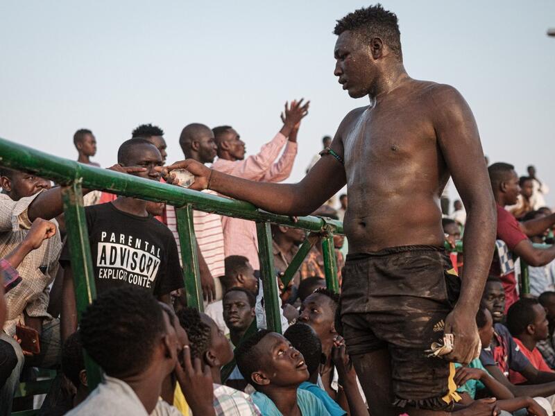 A Sudanese wrestler receives money from spectators after winning during a traditional Nuba wrestling match at the Haj Youssef stadium in the district of Khartoum.  Yasuyoshi CHIBA / AFP