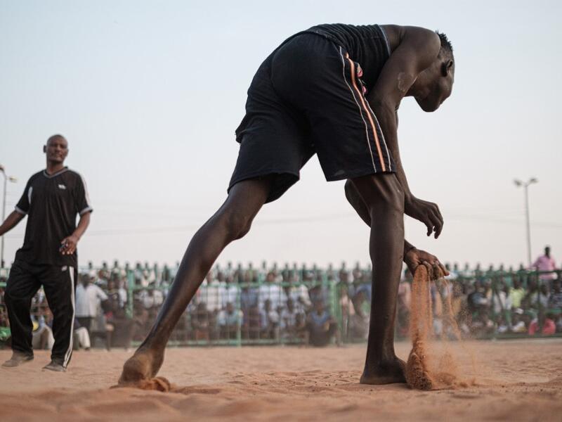A Sudanese wrestler scoops sand during a traditional Nuba wrestling match at the Haj Youssef stadium in the district of Khartoum.  Yasuyoshi CHIBA / AFP