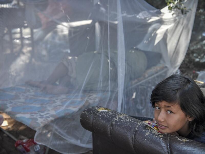 A girl gazes at the makeshift part of the Samos refugee camp, just above the island's capital city of Vathy.  LOUISA GOULIAMAKI / AFP