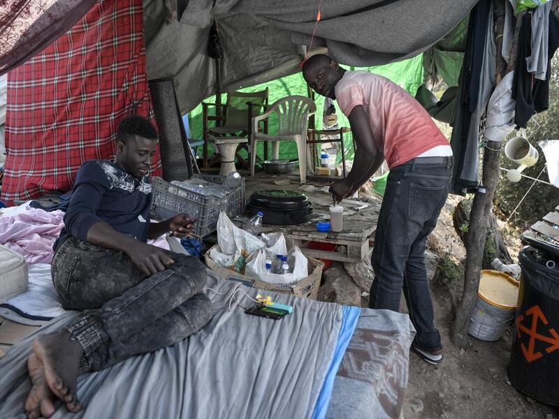 Migrants prepare tea at the makeshift refugee camp on the island of Samos just above the island's capital city of Vathy.  LOUISA GOULIAMAKI / AFP