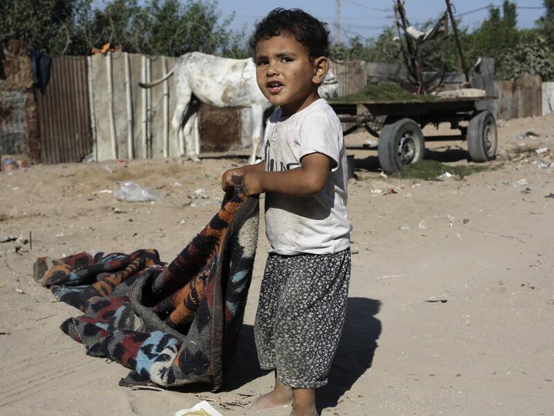 A Palestinian boy pulls a blanquet at an impoverished neighbourhood in Gaza City on July 4, 2019.  MOHAMMED ABED / AFP