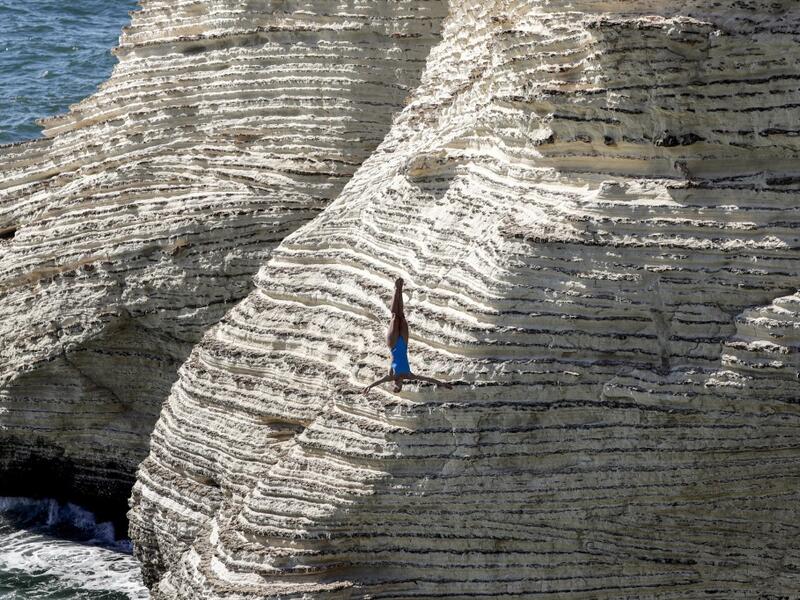 A cliff diver jumps from a platform on the landmark Raouche sea rock off the coast of the Lebanese capital Beirut on July 14, 2019, during the women's 2019 Red Bull Cliff Diving World Series.  ANWAR AMRO / AA / AFP