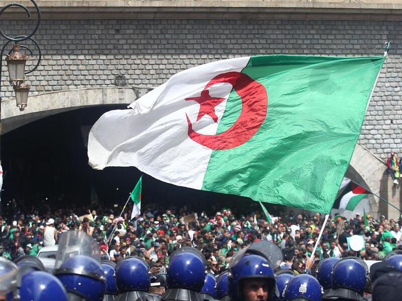 Algerian protesters wave a national flag as security forces stand guard during an an anti-government demonstration in Algiers on April 12, 2019. AFP Algerian protesters wave a national flag as security forces stand guard during an an anti-government demonstration in Algiers on April 12, 2019. AFP