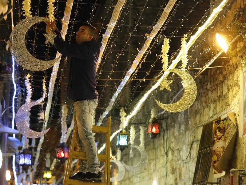 A Palestinian man decorates with lights near the entrance of the al-Aqsa mosque compound, in the old city of Jerusalem on May 4, 2019, as Muslims around the world prepare for the announcement of the fasting month of Ramadan. AHMAD GHARABLI / AFP