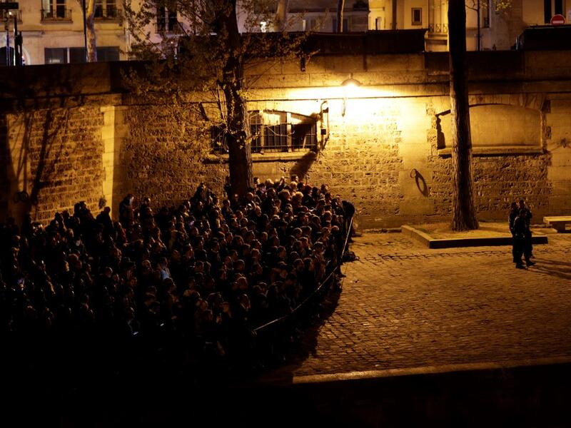 People look at the fire engulfing the Notre-Dame Cathedral in central Paris from the quai de la Tournelle on the banks of the Seine river on April 15, 2019. Geoffroy VAN DER HASSELT / AFP