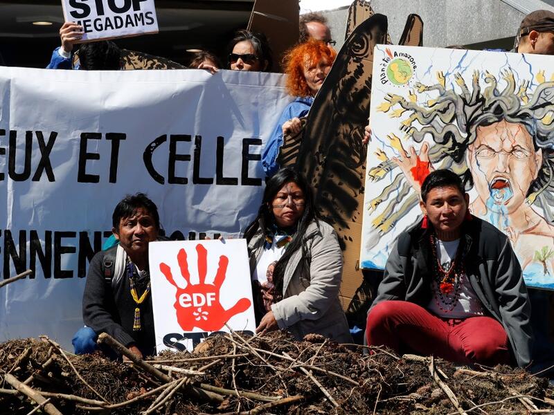Members of indigenous tribes from the Amazon demonstrate alongside activists of 'Extinction Rebellion' (XR) against large hydroelectric dams in front of the Grande Arche de La Defense in Puteaux, northwest of Paris, on May 14, 2019. FRANCOIS GUILLOT / AFP