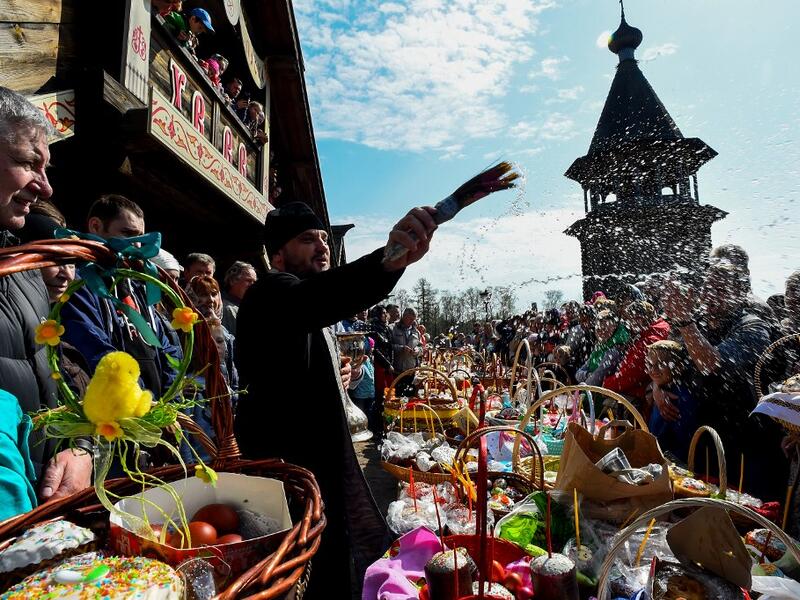 An Orthodox priest blesses traditional cakes and eggs on the eve of Orthodox Easter at Saint Petersburg's Pokrovsky Cathedral on April 27, 2019.  Olga MALTSEVA / AFP