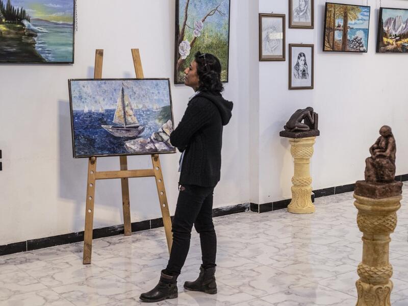 Amal al-Attar, a 37-year-old artist, looks at her artworks on display during an exhibition at the first cultural centre to open since ISIS rule ended in the eastern Syrian city of Raqa on May 1, 2019. DELIL SOULEIMAN / AFP